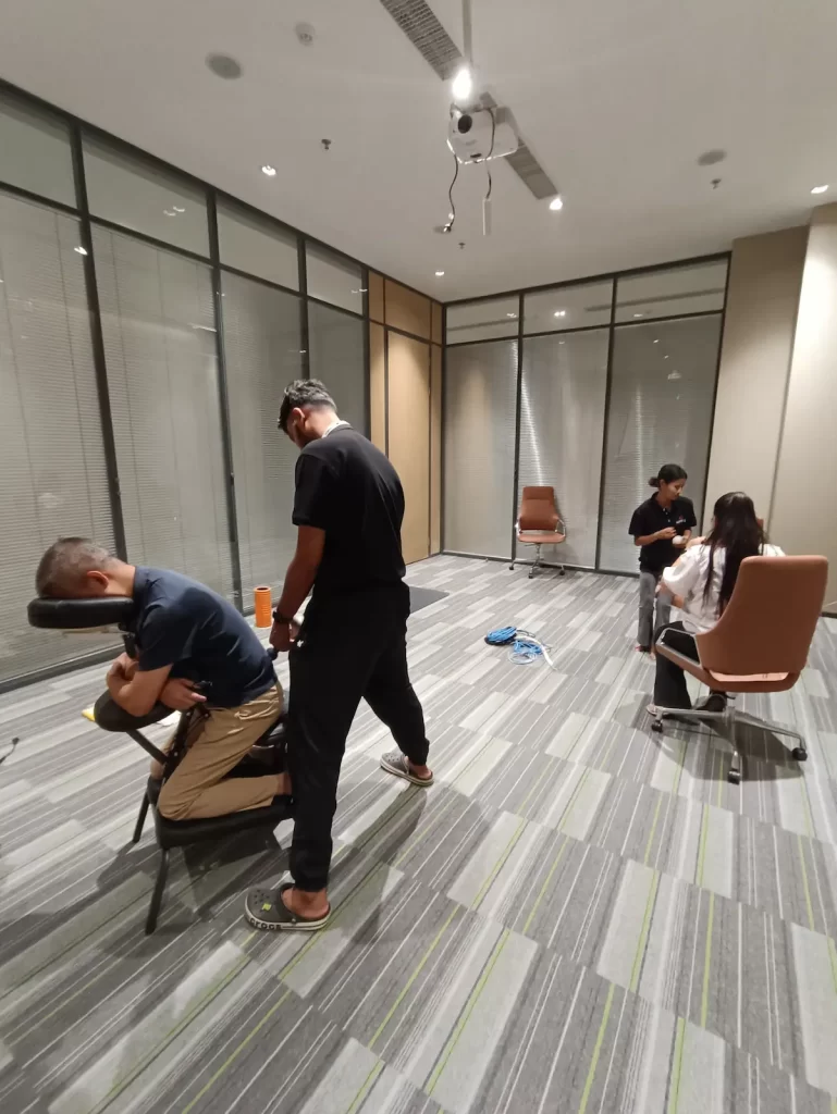 Physiotherapist using a portable massage chair to provide stress relief for employees in Phnom Penh
