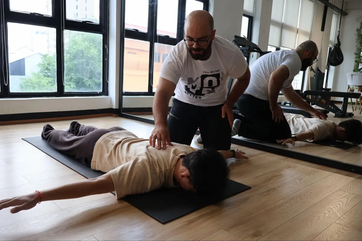 Physiotherapist providing hands-on manual correction to a client during a fitness session to ensure safety
